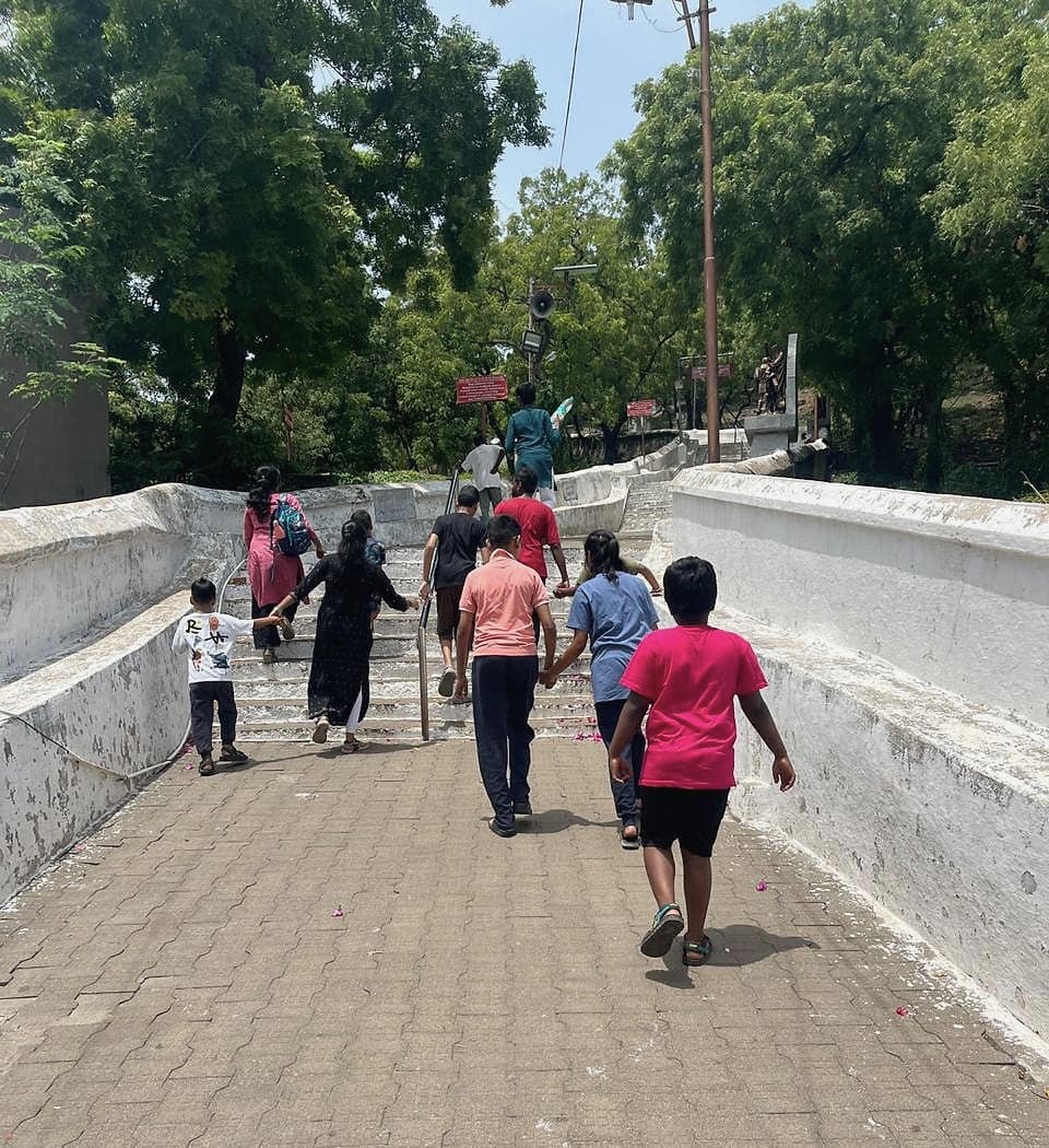 A group of children and adults walking up a flight of steps together, some holding hands, seen from behind.